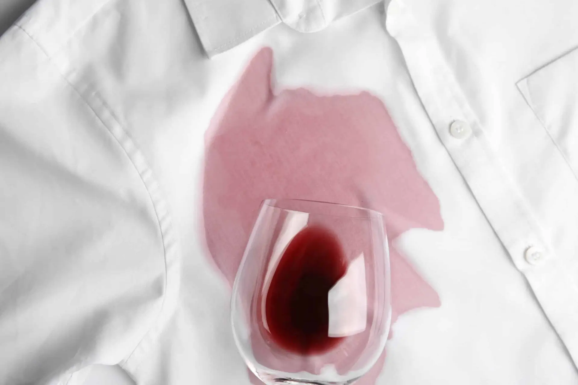 a glass of red wine on a white shirt