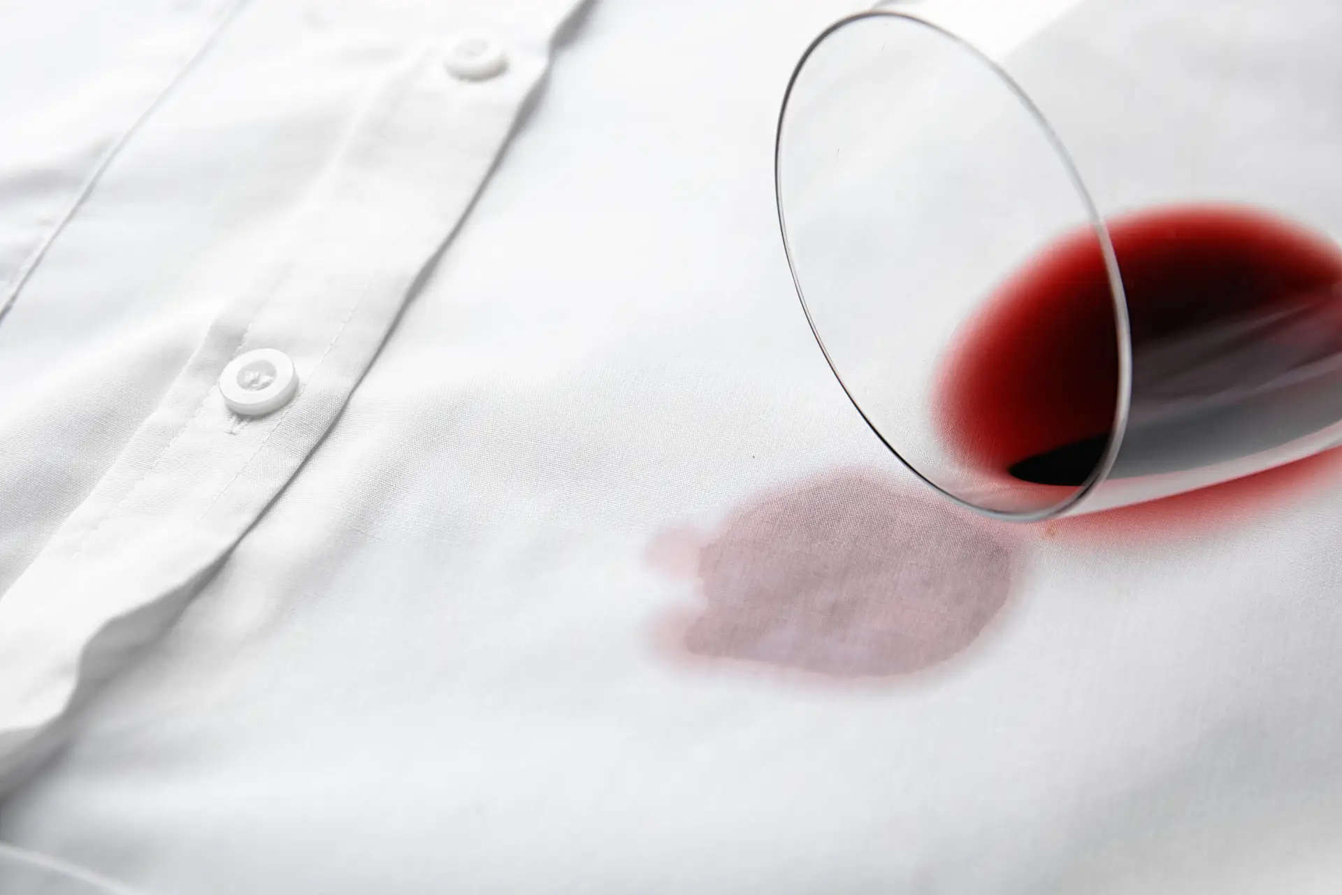 a glass of red wine on a white shirt